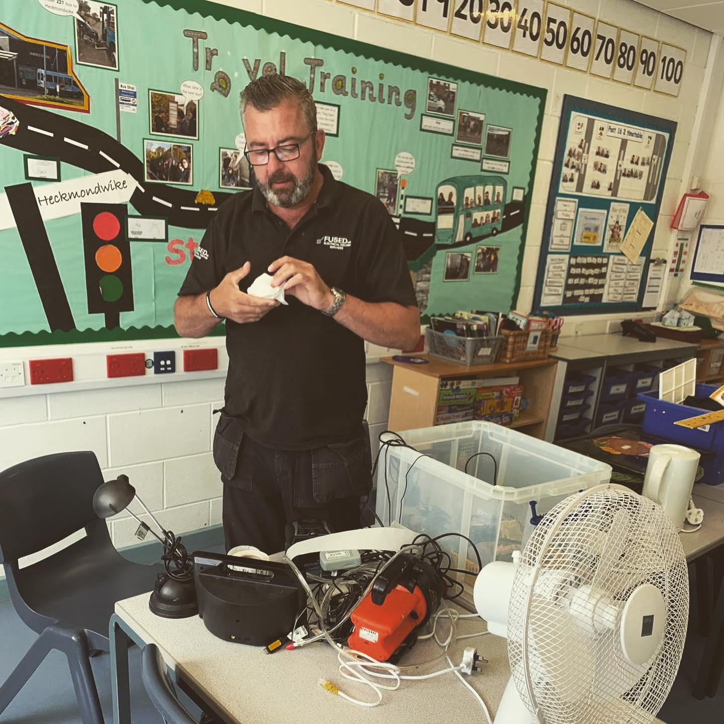 FUSED UK engineer PAT testing appliances in a school